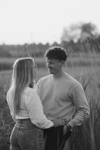 Een stelletje kijkt elkaar liefdevol aan in een hoog grasveld in Den bosch, vastgelegd door Sharon Kastelijns Photography.
