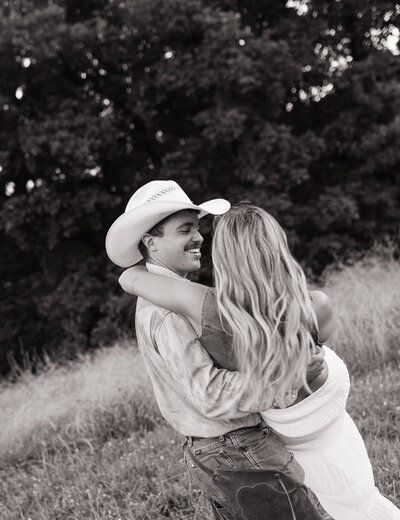 A romantic black and white moment from this western-inspired couples session—he picked her up and spun her around as they laughed under the open East Tennessee sky. This candid, movement-filled shot captures the spirit of connection and adventure in timeless documentary style.