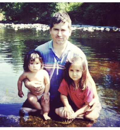 Virginia wedding photographer in a black dress and black shoes posing with a hand on her hip in a spring wild flower field in Shenandoah National Park with rolling hills and mountains in the distance