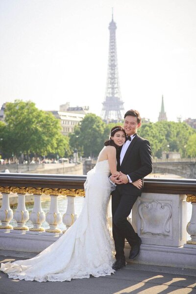 Couple hug happily in front of Eiffel Tower
