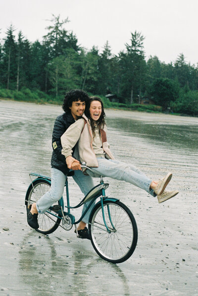 A couple rides their bike together on a beach in Tofino, BC