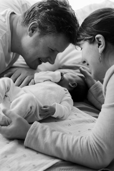 Een gezin poseert liefdevol met hun pasgeboren baby tijdens een fotoshoot in een mooie omgeving.