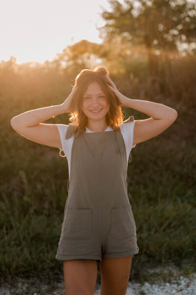 Teenage girl places both hands in her hand and smiles.