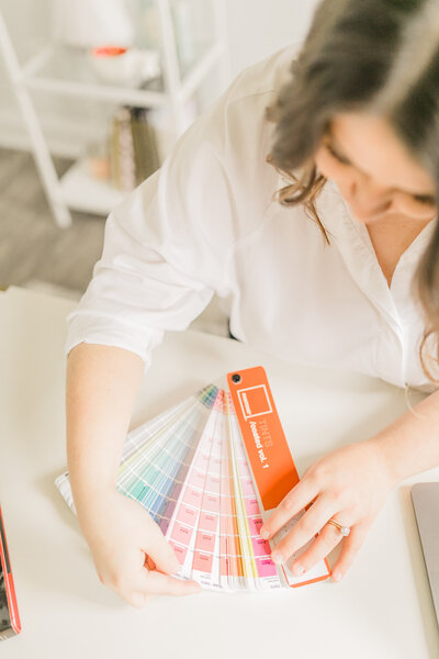 Woman sitting at desk flipping through Pantone Color Swatches