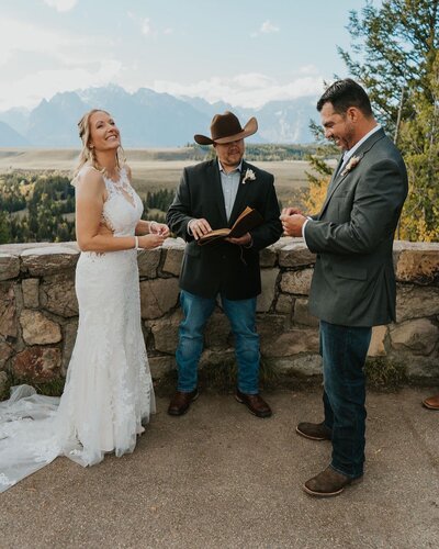 Elopement photographer Adriana Montoya Photo. An elopement taking place in Eastern Idaho with mountains in the background. The bride and groom are about to exchange rings.