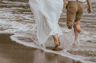 Big sur elopement couple running down the beach