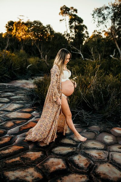 Pregnant woman in floral robe walking on cobbled road