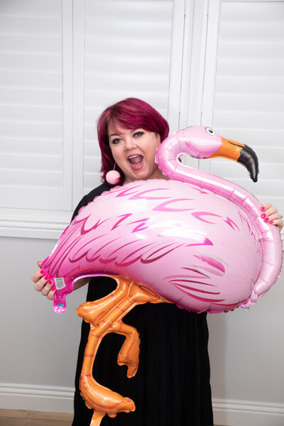 Women holding flamingo balloon smiling