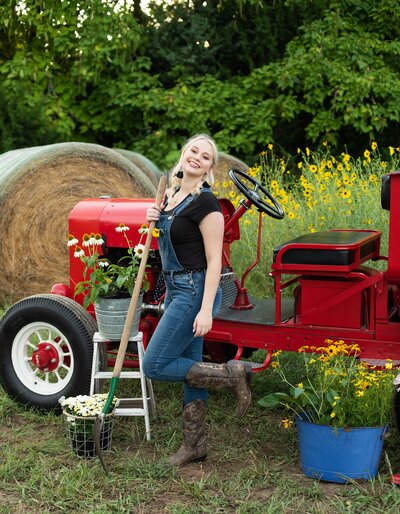 high school senior pictures farm themed shoot girls dreessed in ovralls posing with red tractor