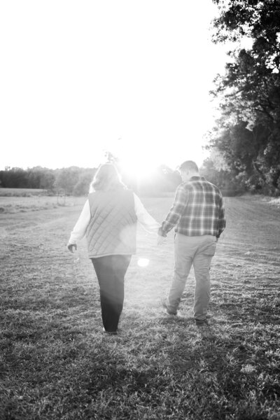 Engaged couple walking hand-in-hand on the family farm in Kentucky.
