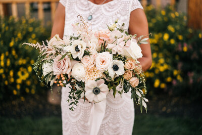 Bride in lace dress holding blush bridal bouquet with anemones and roses in Powell Butte, Oregon