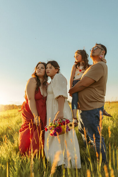 A family of four embracing in the Ames sunset.