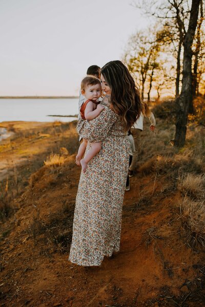 A mom holding her baby boy in her arms while pressing her nose to his cheek by Grapevine Lake in Flower Mound, Texas