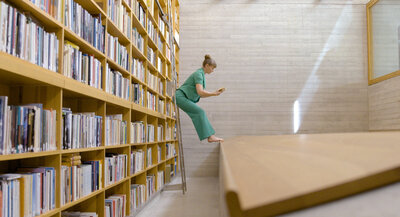 Woman balances on bookshelf