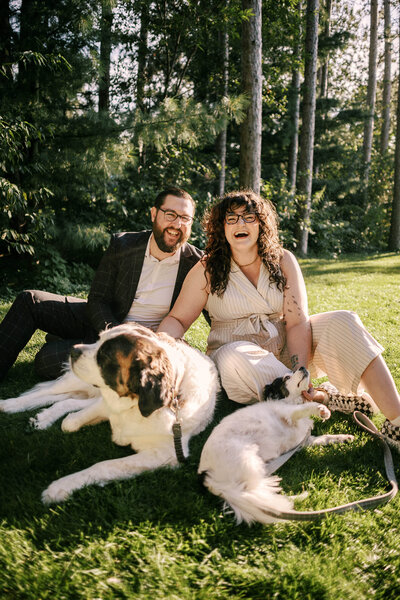 Bryan and Olivia of O & B Photo Co where dress clothes while sitting in a grassy yard with their two dogs on a sunny da