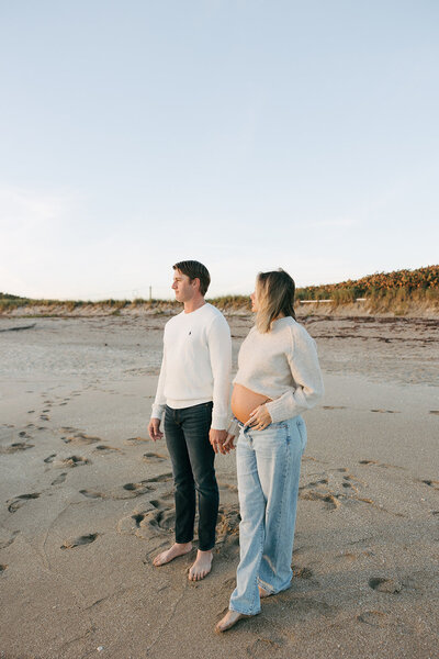 couple holding hands on a beach looking at the sunrise