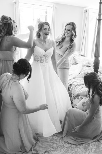 a bride getting ready with her bridemaids fluffling out her dress in a mdoern farmhouse wedding venue in new jersey