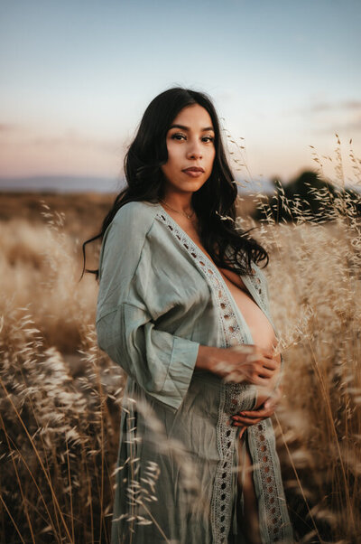 Pregnant mother in a blue kimono in a golden field at blue hour.