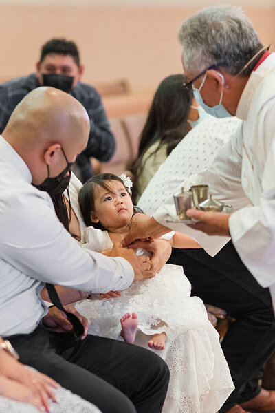Baby looking at priest during baptism in Carson church