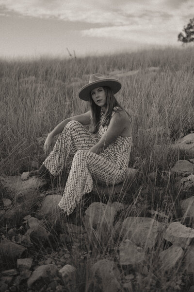Photographer Marcie Jean sitting on a rock wearing a wide brim hat.