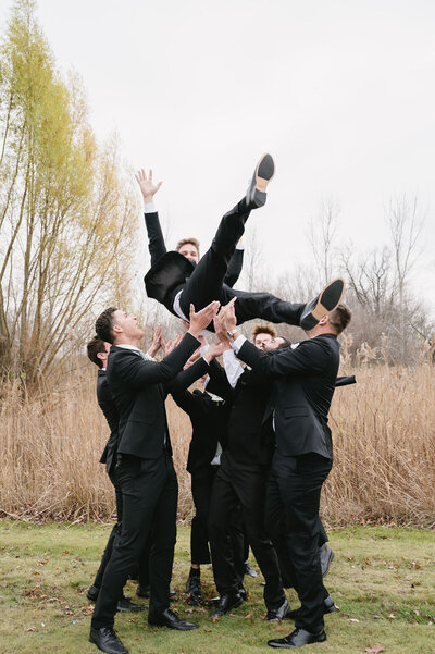 groomsmen throwing groom into the air playfully