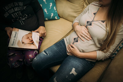 Pregnant woman sitting on couch with laptop and phone during virtual midwifery support