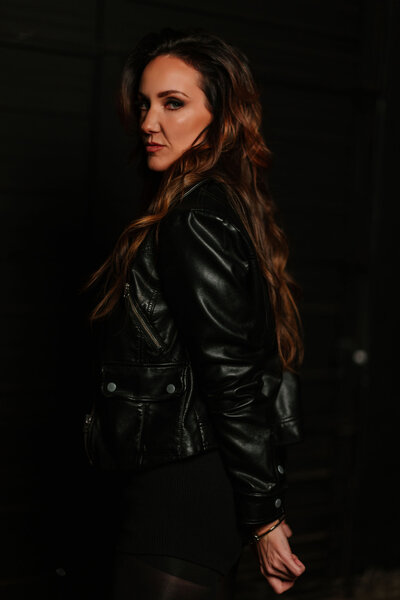 Juliet Trnka looking over her shoulder, view from behind, wearing a black leather jacket