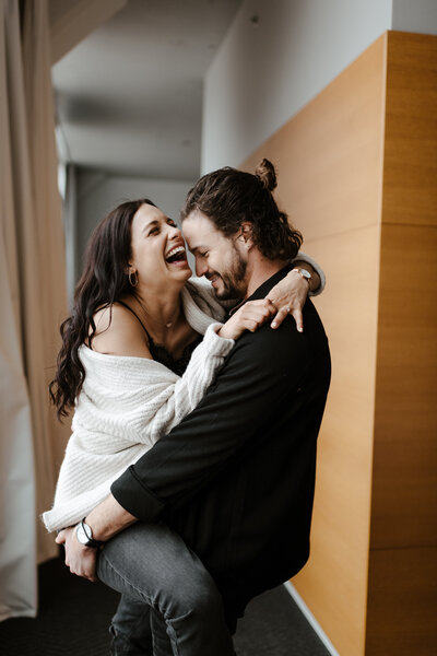 Couple laughing together playing on the bed during their in home session