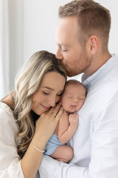Parents hugging new baby between them