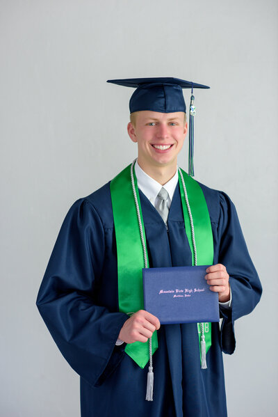 Senior boy in graduation cap and gown in portrait studio in Boise.