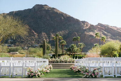 Outdoor ceremony setup with white chairs and floral aisle at Mountain Shadows wedding venue in Scottsdale, Arizona, with Camelback Mountain views.