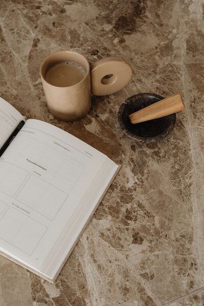 A notebook on a desk with a cup of coffee