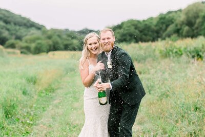 Bride and groom popping champaign at park, taken by minneapolis photographer Kacey Wyrick