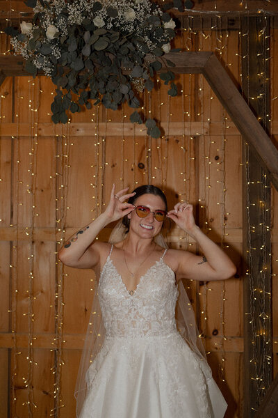 Bride in a white gown smiling while wearing stylish sunglasses