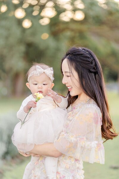 Asian girl in Needle and Thread peaches dress holding baby in Brisbane South.