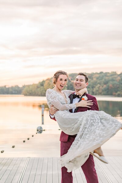 Bride and groom laughing in the sunset as the groom holds his bride and spins in a circle - fall wedding colors