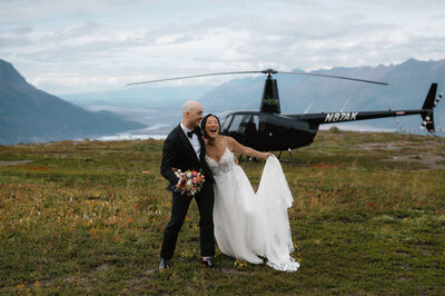 Bride and groom stand in front of helicopter