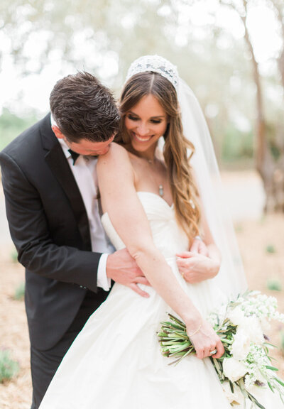 A groom tenderly embraces his bride in a classic black-and-white wedding moment, reflecting the love and joy of a WINK! Weddings celebration.