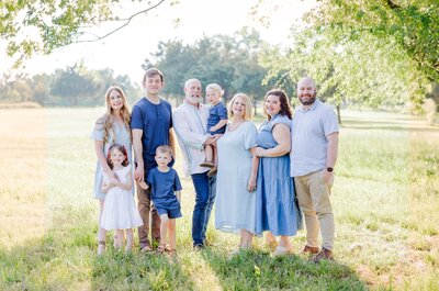 A large extended family stands in a field together smiling for their Little Rock Family Photographer