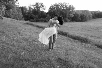 Candid moment of couple laughing as one spins the other in a joyful embrace, surrounded by endless nature. 