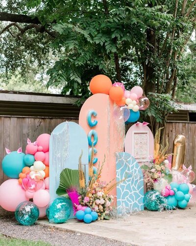 Colorful blue and coral arch backdrop design with balloons and flowers