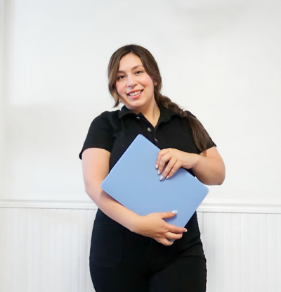 Real Estate Web Designer Marie Alaniz in a black top holding a laptop with a blue case