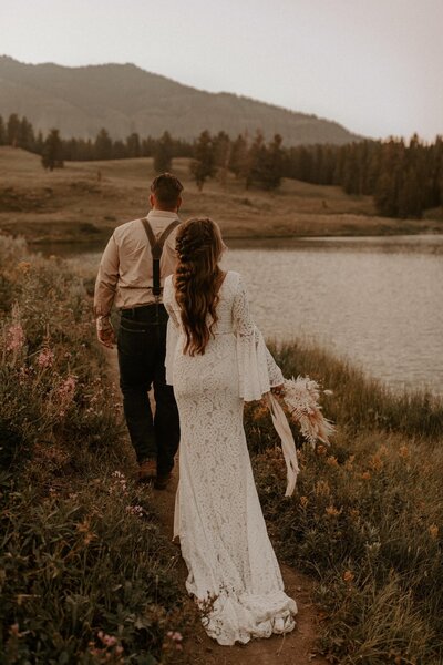 Bride and groom walking by a river in Yellowstone National Park