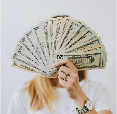 Image of a budget friendly woman, holding money in the air