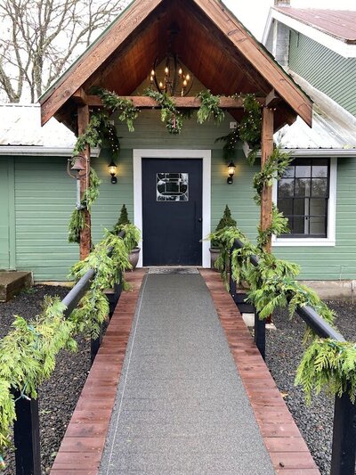 Festive holiday garlands shown on railings and door representing  floral design services by Flowers and Thyme for holiday decor.