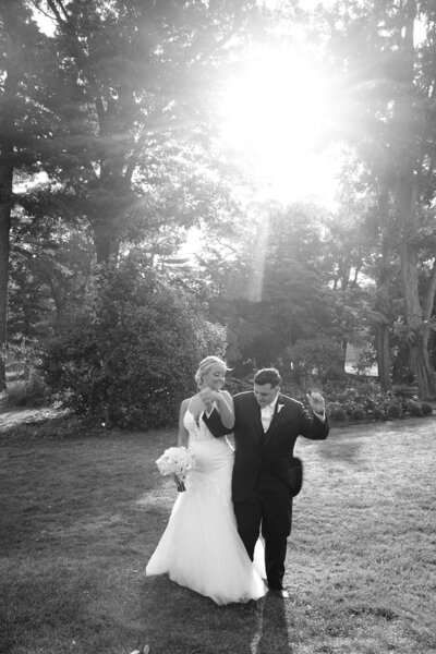 black and white image of bride and groom walking hand in hand