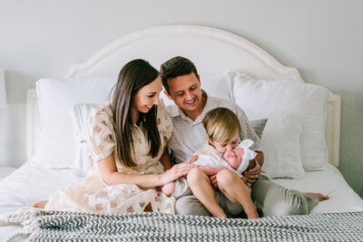 Parents admiring their oldest son kissing his newest baby sister