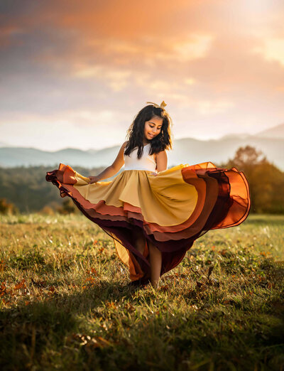 A little girl twirling in the grass at sunset in a beautiful field on the biltmore estate