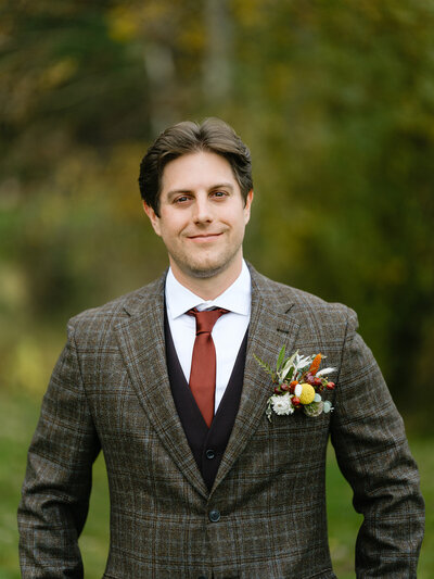 Groom in tweed suit with pocket square style fall boutonniere in Sisters