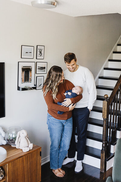 couple on bed holding newborn daughter during newborn portraits
